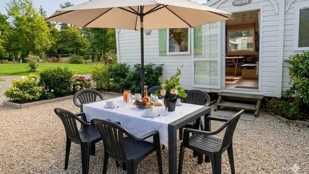 Una mesa de patio con sillas, una sombrilla y una planta en maceta.