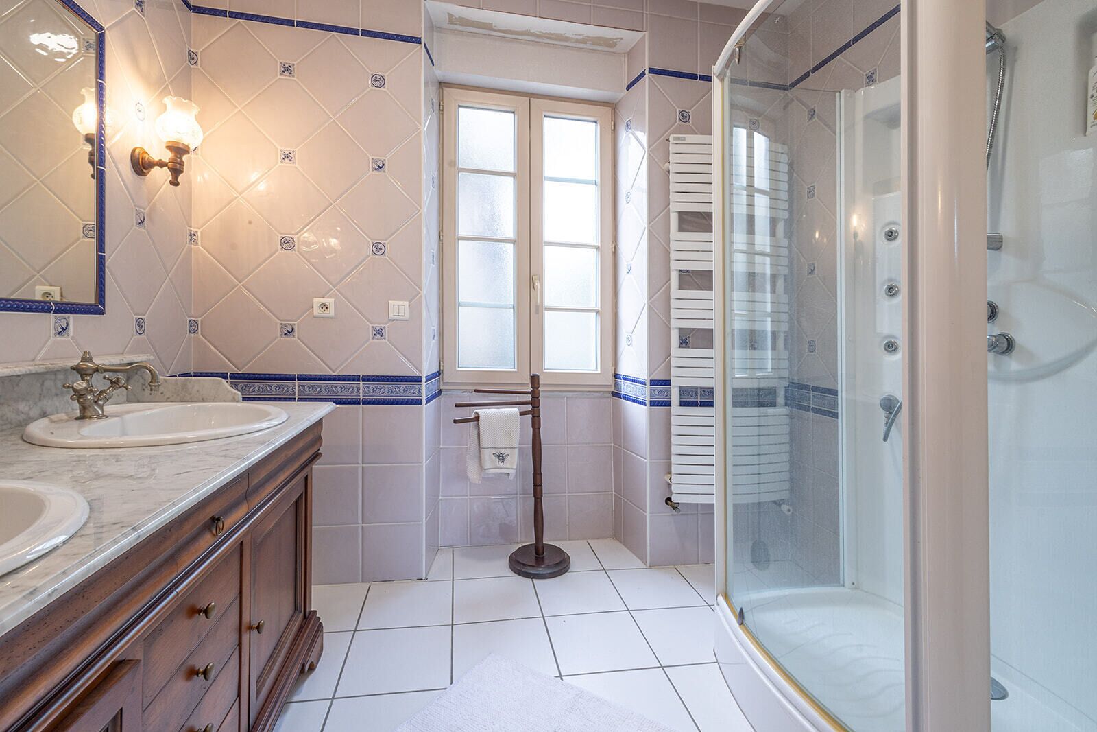 Un baño con dos lavamanos, un espejo, una ventana, un perchero para toallas y una zona de ducha.