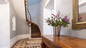 A staircase with a wooden handrail and a metal bucket of flowers on a wooden counter. - Lovely french house in a medieval village - private pool, ping pong & game room (Vianne)