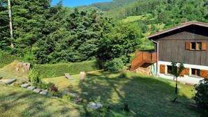 Un chalet rustique doté d’une terrasse en bois et d’un escalier en pierre menant à une porte en bois.