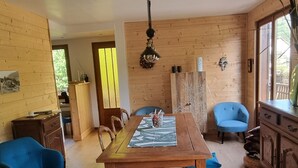 Un intérieur en bois avec une table à manger, des chaises bleues et un buffet en bois.