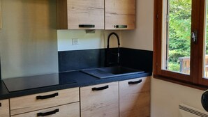 Une cuisine moderne avec des meubles en bois, un plan de travail noir et une fenêtre donnant sur un paysage verdoyant.