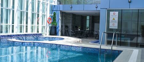 A swimming pool with blue tiles, a lifebuoy, and a potted plant.