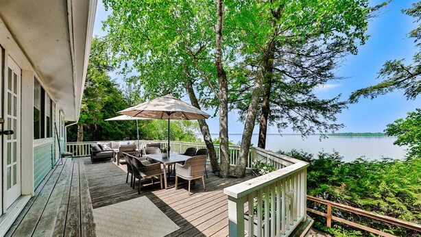 Une terrasse en bois avec des meubles d’extérieur, une table et un parasol.