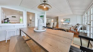 Une cuisine spacieuse avec une table et des chaises en bois, un luminaire suspendu et une vue sur la salle à manger.