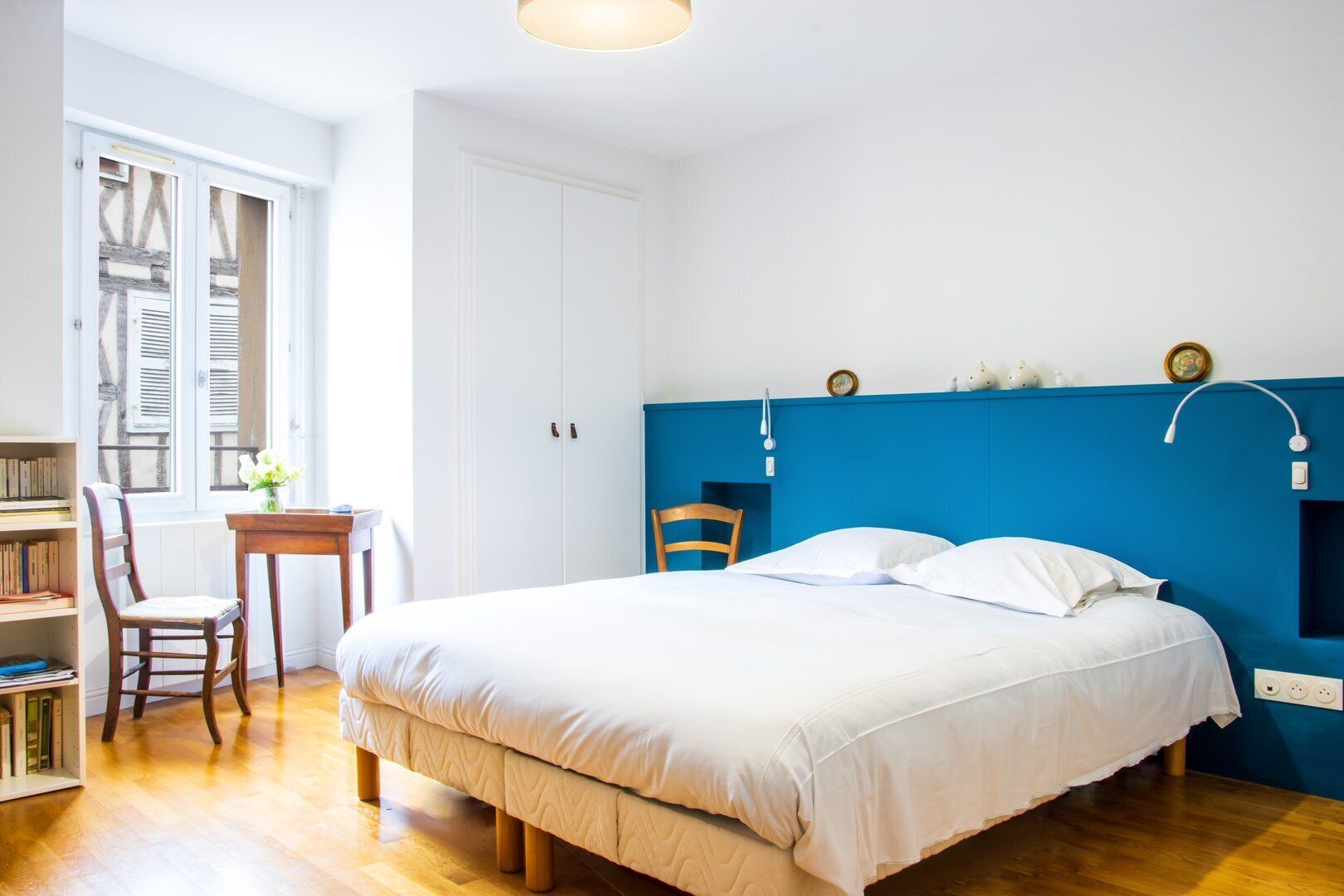 A bedroom with a bed, a desk, a chair, and a bookshelf.