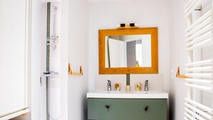 A bathroom with a green vanity, a wooden-framed mirror, and a white towel rack.