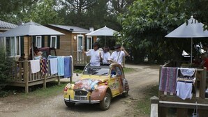 A yellow car parked in front of a wooden structure with a covered porch.