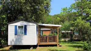 A small cabin with a porch and a window with blue shutters.