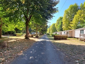 A road lined with trees and mobile homes. - Camping 3 étoiles - Piscine  - eeebbh (Saint-Céré)
