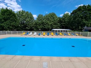Une piscine avec des chaises longues et un espace abrité.
