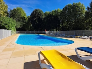 A rectangular swimming pool with a curved edge, surrounded by a tiled deck.