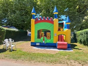 A colorful inflatable castle with a slide and a small window.