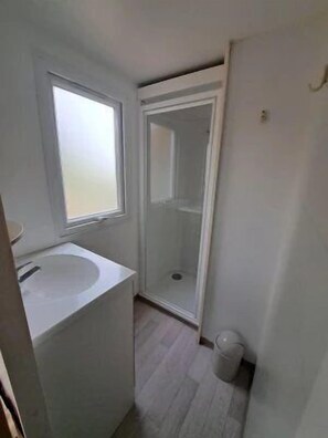 A bathroom with a sink, a window, and a shower.