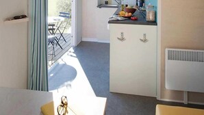 Une cuisine compacte dotée d’une cuisinière intégrée, d’un petit plan de travail et d’une fenêtre donnant sur un jardin.