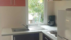 Una cocina compacta con ventana, pileta, cafetera y refrigerador.