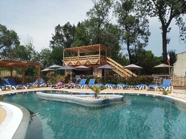 Un espace piscine avec des chaises longues, une terrasse en bois et un drapeau.