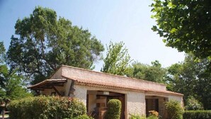 A small stone house with a tiled roof, surrounded by lush greenery and trees. - ZEcamping 3 étoiles piscine chauffée pataugeoire pet friendly locatif TV clim (Roquebrune-sur-Argens)
