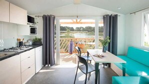 Eine moderne Küche mit Essbereich, Seeblick und einem blaugrünen Sofa.
