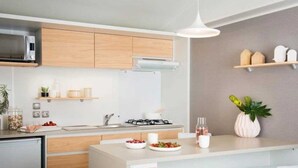 Una cucina moderna con mobili in legno, un piano di lavoro bianco, un forno a microonde integrato e un fornello a gas.