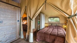 A cozy tented room with a bed, curtains, and a window. - ZEcamping 3 étoiles piscine chauffée locatif TV clim 34m2 (Roquebrune-sur-Argens)