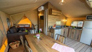 Acogedor interior de cabaña con comedor, cocina y un dormitorio en lo alto.
