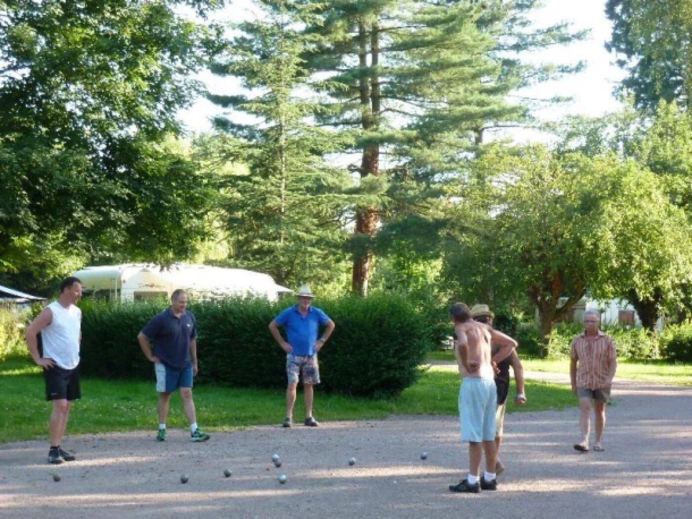 Um grupo de pessoas jogando croquet ao ar livre, com uma carreta ao fundo.