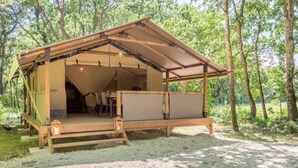 A wooden cabin with a sloped roof, a covered porch, and a gravel ground. - ZEcamping 3 étoiles piscine chauffée pataugeoire locatif TV clim 34m2 (Roquebrune-sur-Argens)