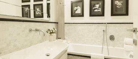 Une salle de bain moderne avec une baignoire sur pieds, une douche et un lavabo entouré de parois en verre.
