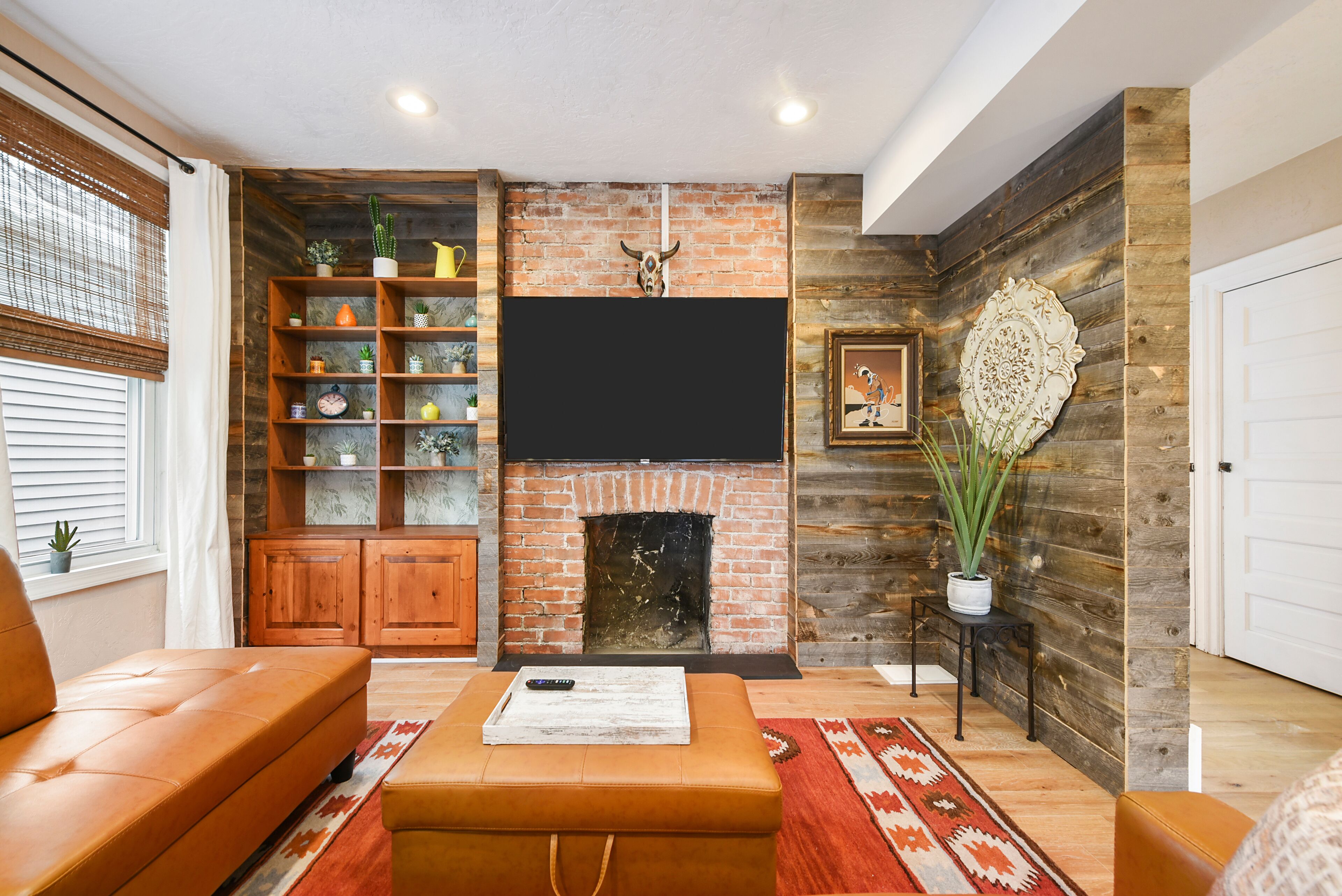 Stylish living area w/ comfy sofa, 65" TV, & wide windows to relax.