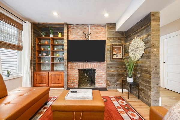 Stylish living area w/ comfy sofa, 65" TV, & wide windows to relax.