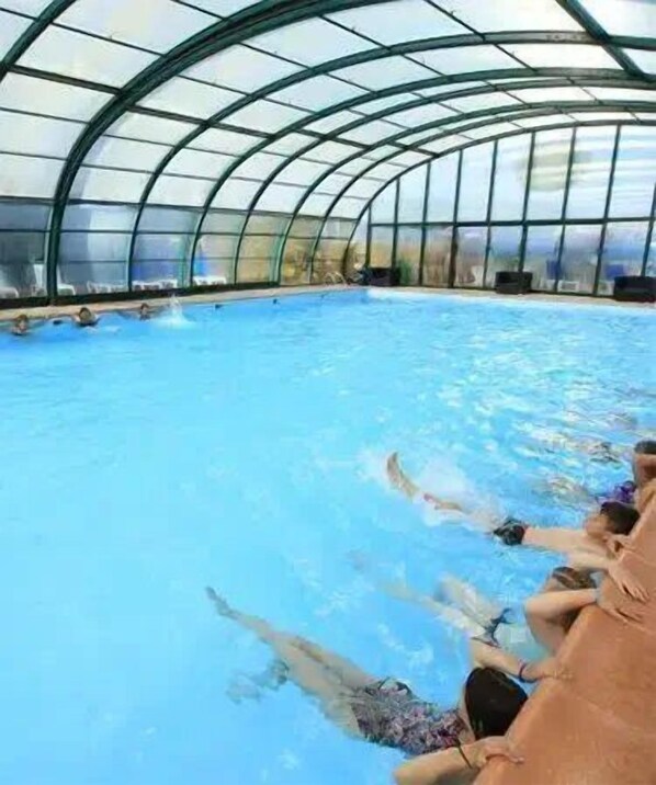 An indoor swimming pool with a curved glass ceiling.