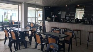 Un restaurante con terraza, barra y vistas al mar.
