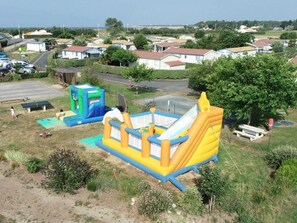 An inflatable bounce house in a grassy area with houses in the background.
