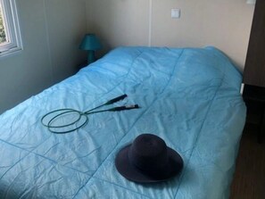 Un letto con una coperta blu, un cappello nero e un oggetto verde sopra il letto.