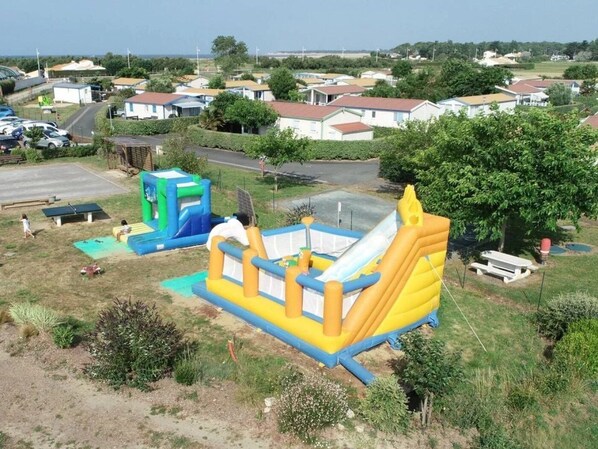A residential area with houses, a road, and an inflatable bounce house in the foreground.