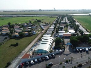 An aerial view of a residential area with houses, a large curved building, and a parking lot.