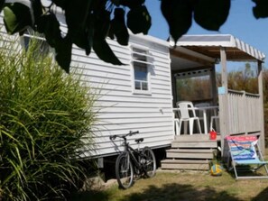 En campingvogn med veranda, cykel og udendørs møbler.