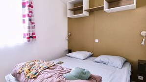 Un dormitorio con cama, almohadas, una colcha colorida y un cabecero con estantes integrados.