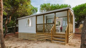 A single-story mobile home with a wooden deck and a covered porch. - ZEcamping 4 étoiles animé pataugeoire locatif TV clim 41m2 4 pers (Alghero)