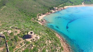 An aerial view of a coastal area with a beach, greenery, and a clear blue sea. - ZEcamping 4 étoiles animé pataugeoire locatif TV clim 41m2 4 pers (Alghero)