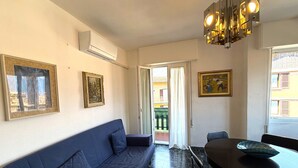 A living area with a sofa, a dining table, and a chandelier. - Casa Liver Pieve balcony town center (Tremosine)