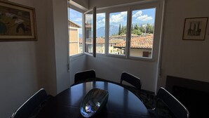 A dining area with a round table, chairs, a glass bowl centerpiece, and a painting on the wall. - Casa Liver Pieve balcony town center (Tremosine)