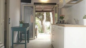 Una cocina estrecha con armarios blancos, techo de madera y vistas al exterior.