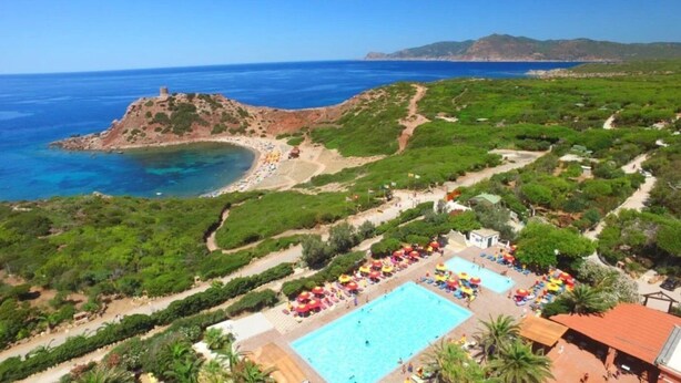 A resort with a large swimming pool, beach access, and lush greenery.