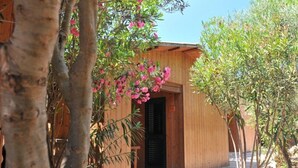 A wooden building with a door, surrounded by trees and pink flowers.