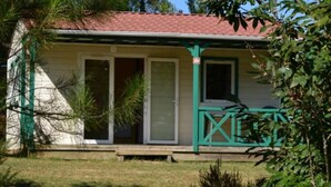 A single-story house with a red-tiled roof, a green porch, and a small front yard. - ZEcamping 4 étoiles animaux acceptés tennis pataugeoire (Tamniès)