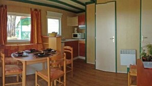 Ein kompakter Wohnbereich mit Essplatz, Küchenzeile und einer Tür zu einem weiteren Zimmer.