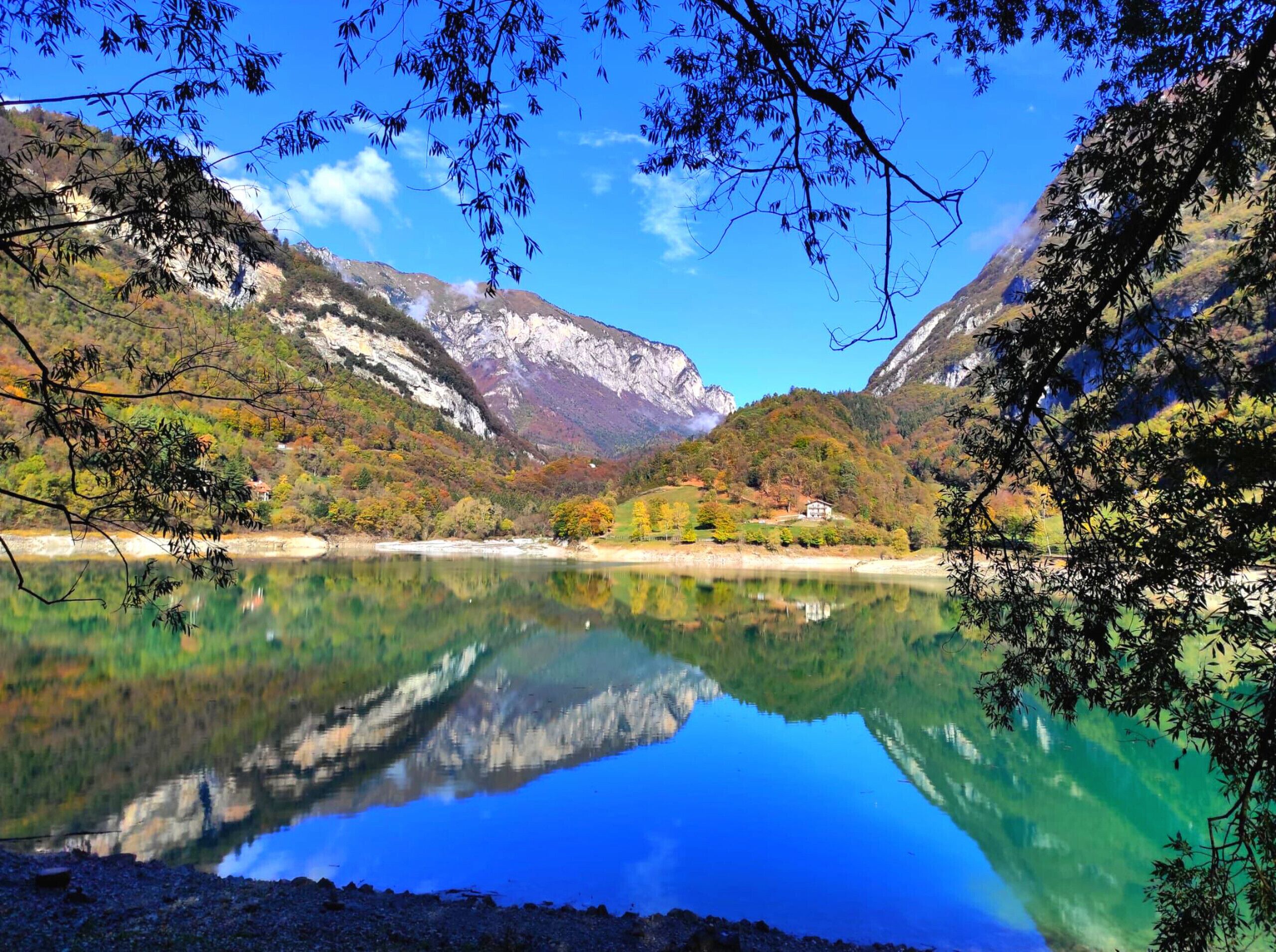 A serene lake with clear reflections of surrounding mountains and trees.