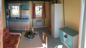 A compact kitchen with a sink, stove, and cabinets. There is a dining area with a table and chairs.